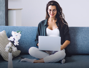 ragazza con pc bianco su un divano celeste